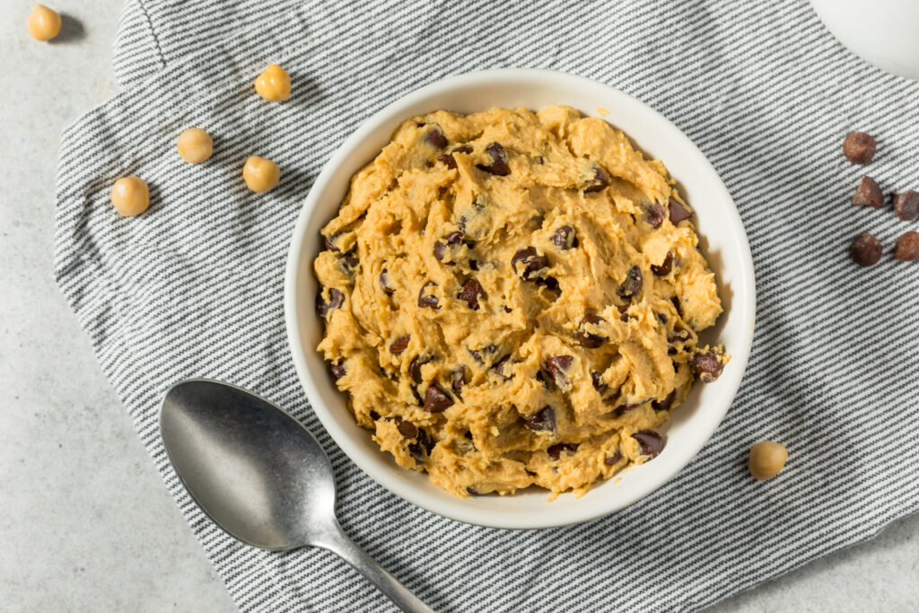 chickpea cookie dough sitting in a white ceramic bowl on a blue stripped dish towel