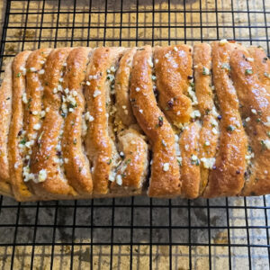 Ancient grain garlic pull apart bread made with fresh milled spelt and kamut, baked golden brown and cooling on a wire rack