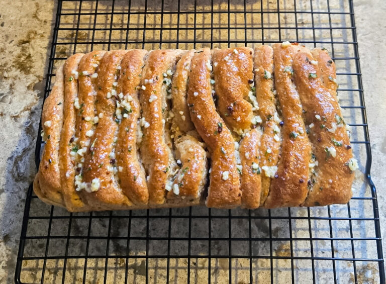 Ancient grain garlic pull apart bread made with fresh milled spelt and kamut, baked golden brown and cooling on a wire rack