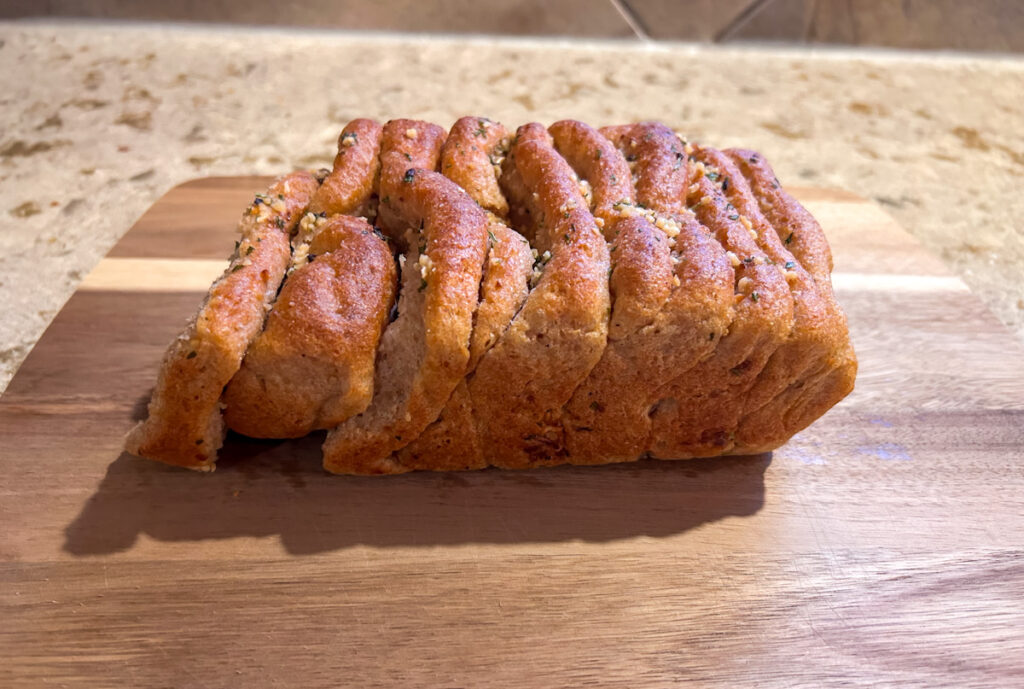 Baked ancient grain garlic pull apart bread sliced and served on a wooden board
